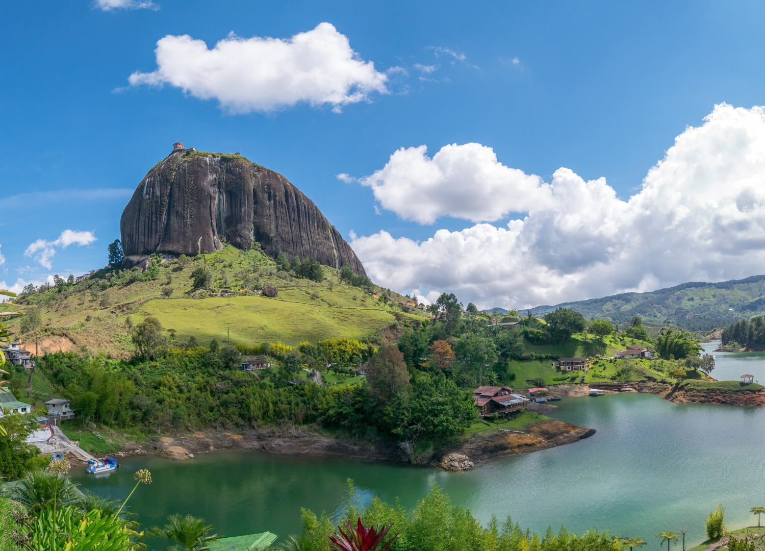 Vista panorámica de Medellín con la emblemática roca del Peñol, rodeada por los hermosos lagos y montañas de la región.